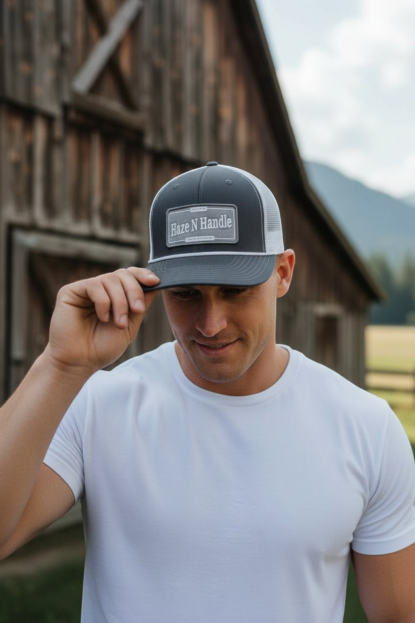 Haze N Handle black and gray trucker cap with rope detail on brim and woven patch. Adjustable back.