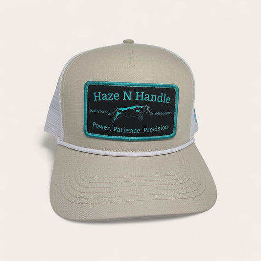 Haze N Handle stone trucker hat with white mesh back, rope detail, and embroidered teal and black patch.